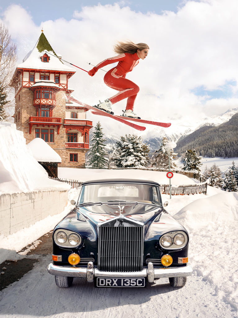 A woman in vintage ski attire soars gracefully over a classic Rolls-Royce in the snowy Alps in The Alpine Jump, a Signed Limited Edition fine art print by Paul Fuentes,  a surreal blend of elegance, adventure, and cinematic winter style.