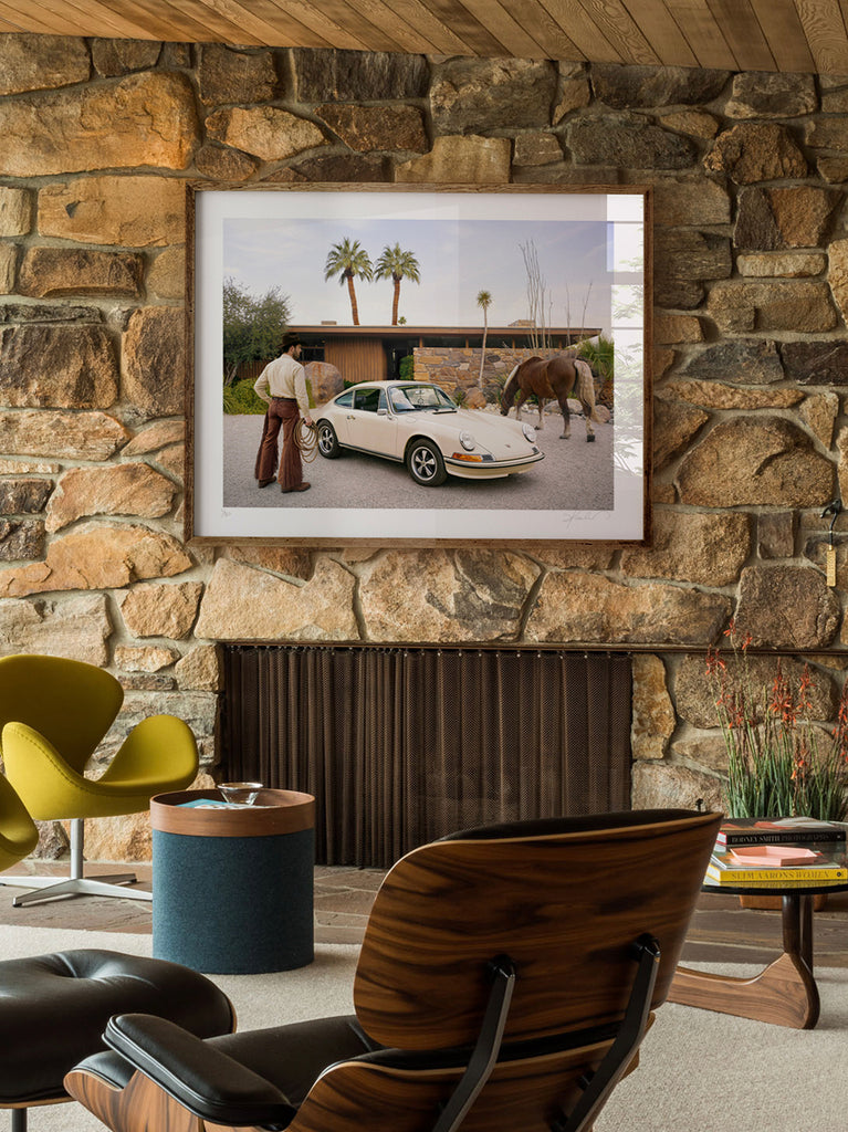midcentury interior with a framed artwork of a cowboy stands beside a vintage Porsche in front of the iconic Edris House in Palm Springs in Horsepower, a Signed Limited Edition fine art print by Paul Fuentes . A surreal meeting of Western spirit, classic design, and mid-century architecture.
