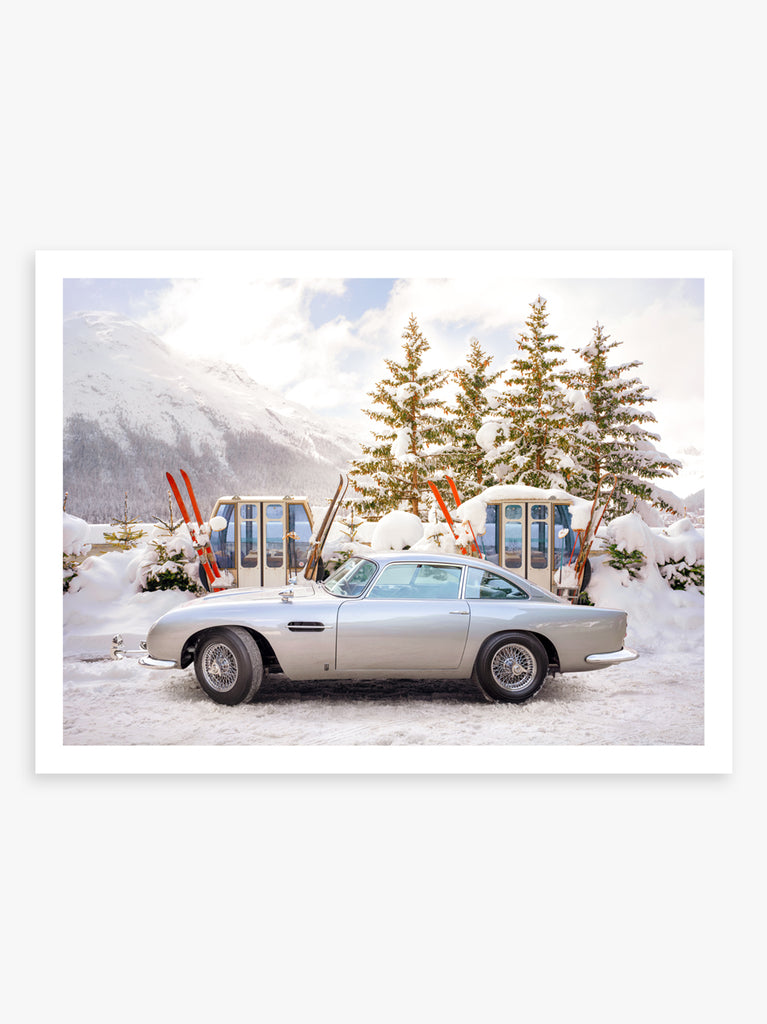 A print featuring a classic Aston Martin DB5 parked in a snowy alpine setting with ski equipment photographed by Paul Fuentes