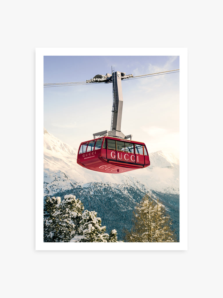 print  featuring a red cable car with the brand name 'Gucci' on it, traveling over a snowy mountain landscape fine art photography by Paul Fuentes.