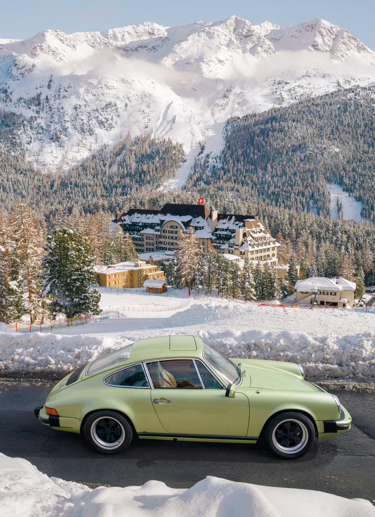 artwork of A classic Porsche driving through the alpine roads of St. Moritz, with the iconic Survetta Hotel and mountain landscape in the background. fine art print by Paul Fuentes.