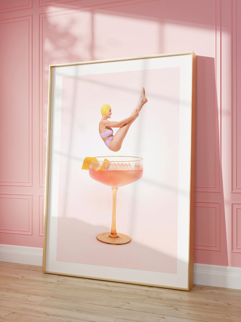 Cosmopolitan art print by Paul Fuentes with a vintage lady diving into a  a oversized cocktail glass, set against a pink background. 