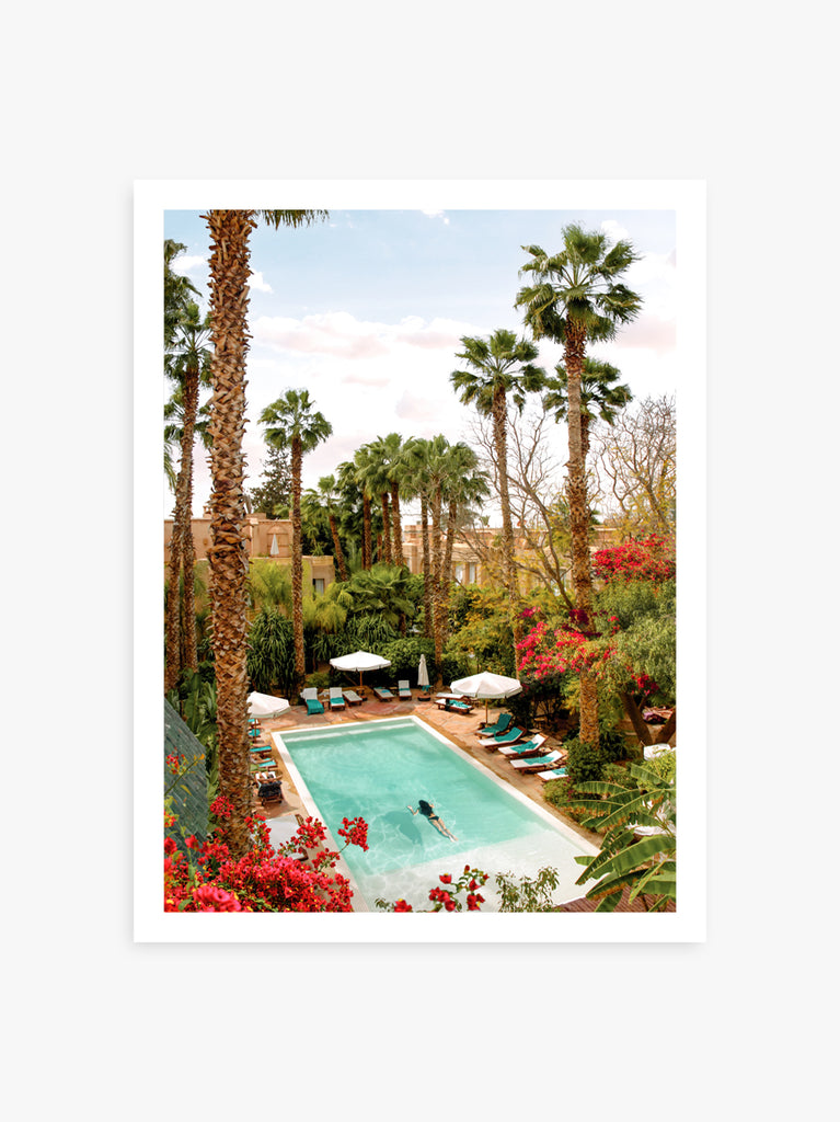 A framed print of a swimming pool surrounded by palm trees and flowers, fine art print by Paul Fuentes