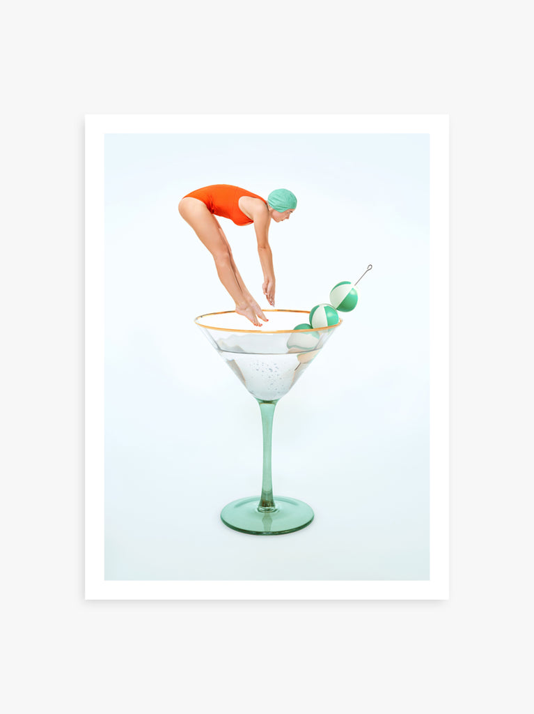 Martini art print by Paul Fuentes with a woman in a red swimsuit diving into a martini glass, with a beach ball olive garnish on the side.
