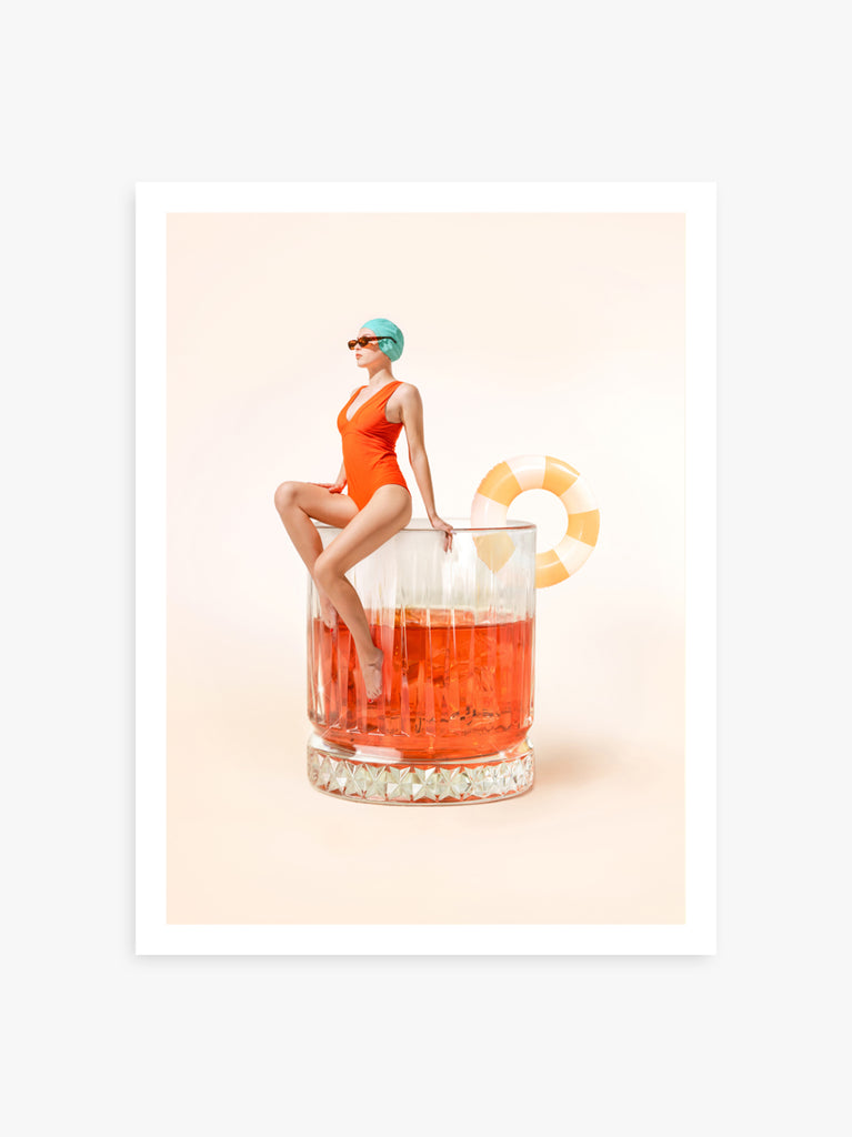 Negroni art print by Paul Fuentes with a  woman in an orange swimsuit sitting on the edge of a glass filled with a red cocktail, against a pastel background