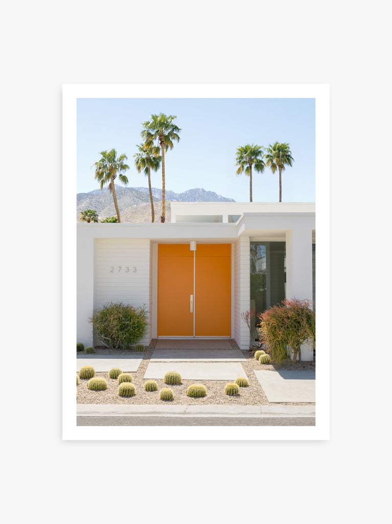 A photograph featuring a vibrant orange front door set against a backdrop of palm trees and a white house in palm springs, fine art photography by Paul Fuentes