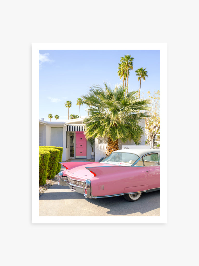 Art print of a classic pink Cadillac car parked in a  Palm Springs home driveway with palm trees in the background, wall art photography by Paul Fuentes
