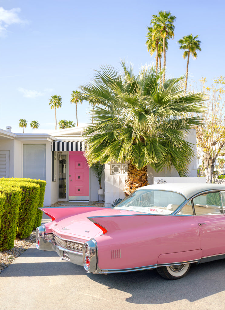Art print of a classic pink Cadillac car parked in a  Palm Springs home driveway with palm trees in the background, wall art photography by Paul Fuentes