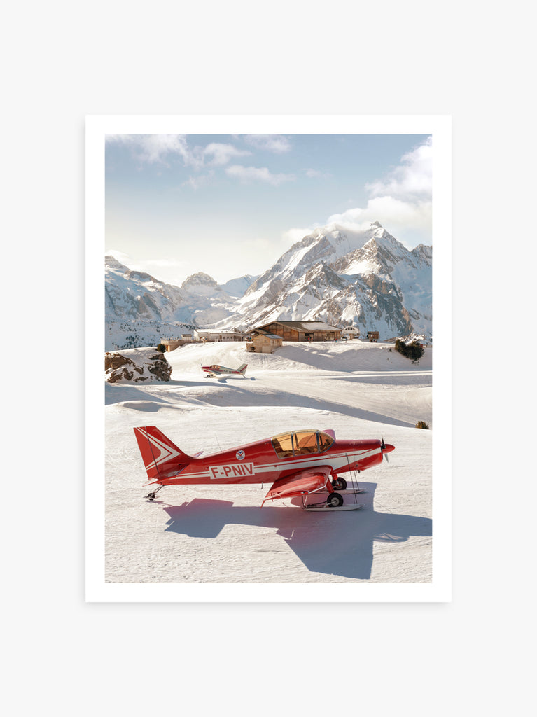 A sleek red aircraft on a remote alpine runway with snow-covered mountains in the background fine art print by Paul Fuentes