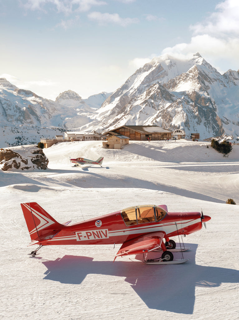 photograph of A sleek red aircraft on a remote alpine runway with snow-covered mountains in the background fine art print by Paul Fuentes