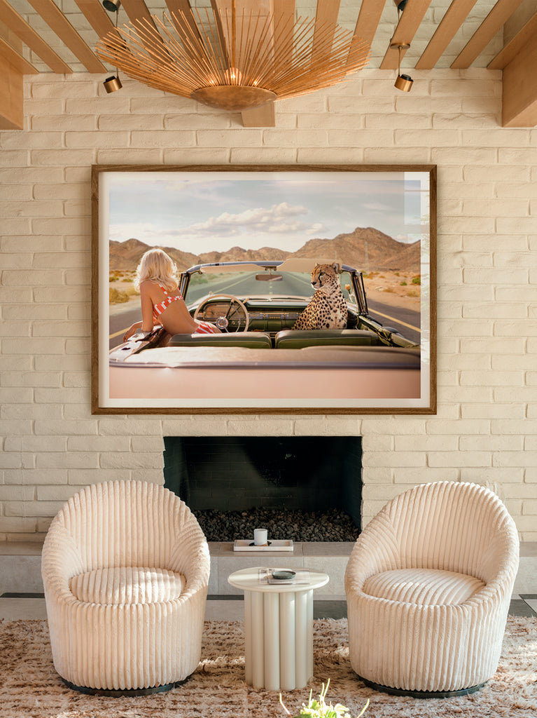 framed artwork of a A woman in a convertible car with a cheetah sitting on the hood, driving through a desert highway, cinematic photograph by Paul Fuentes.