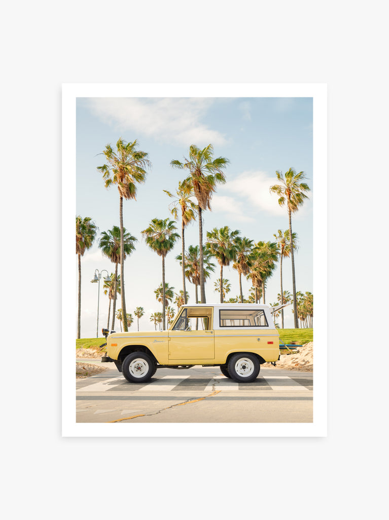A vintage Bronco van parked on a road with palm trees in the background, representing the Venice Beach theme, Fine Art print by Paul Fuentes.
