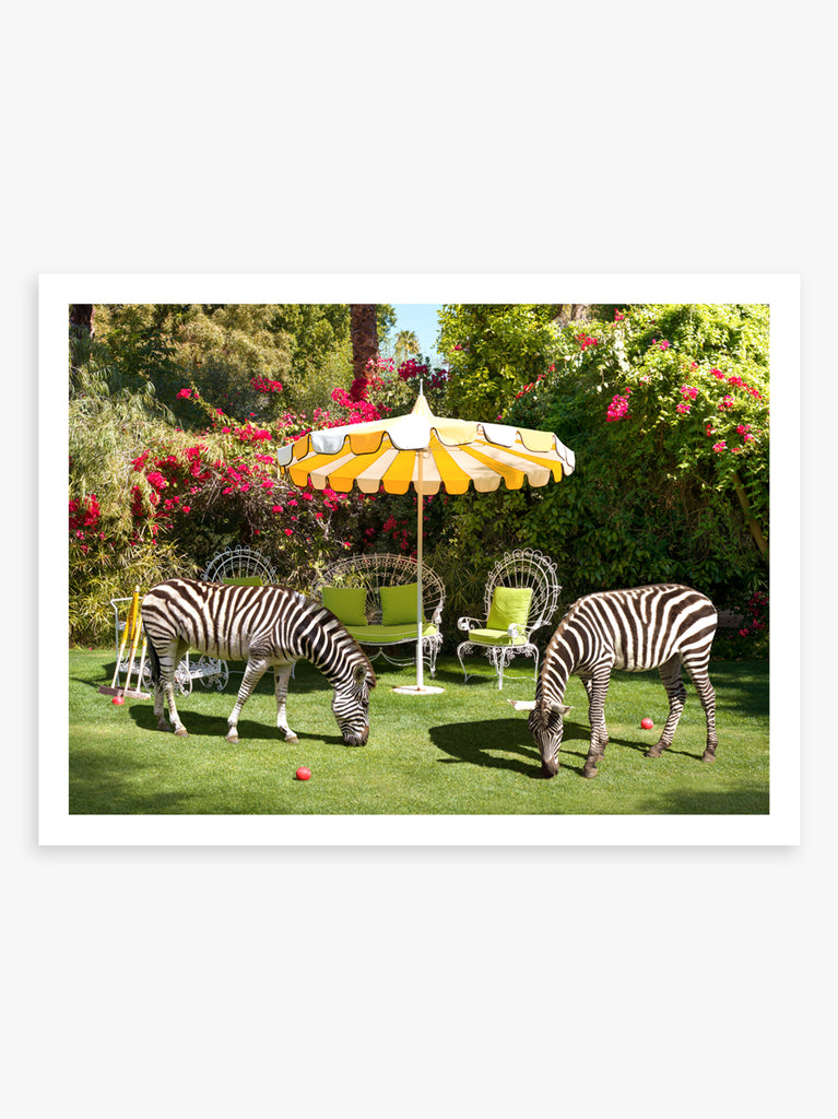 Zebras at The Parker art print by Paul Fuentes showing two zebras on the gras under yellow vintage umbrella at the Parker Palm Springs hotel.