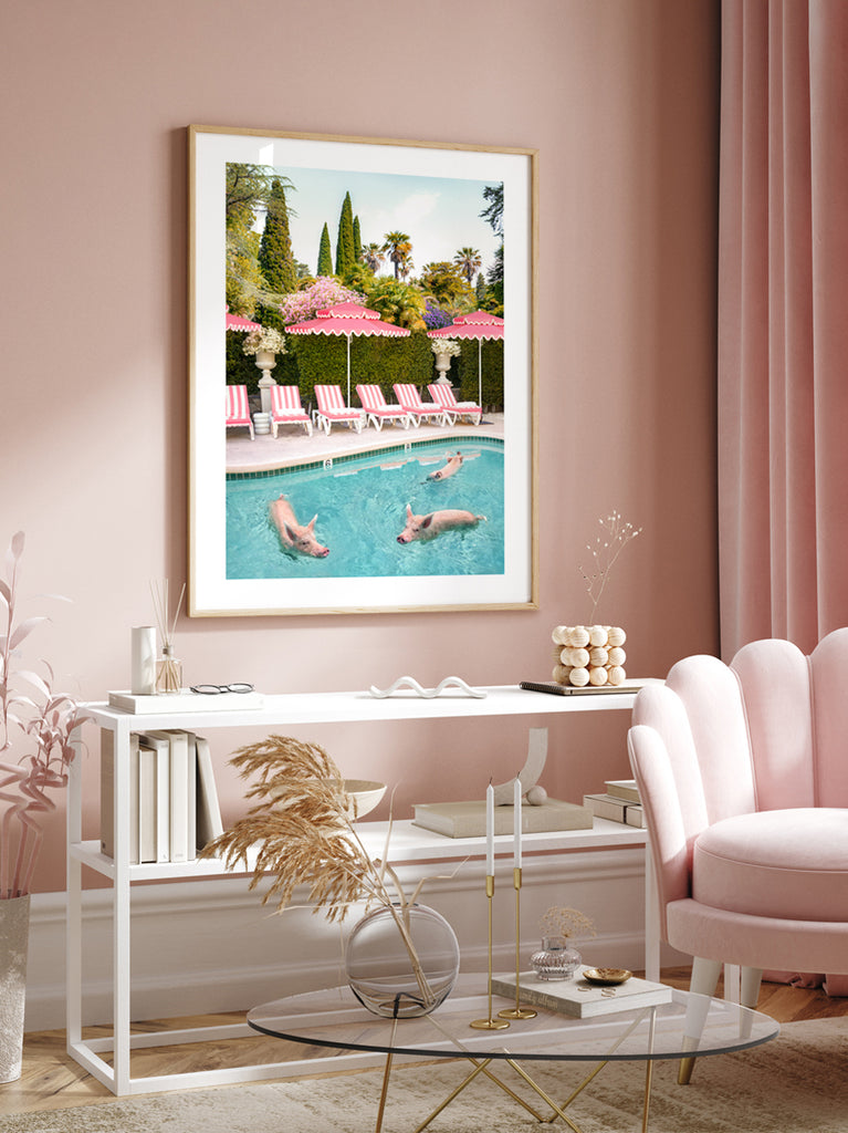 framed artwork of three pigs swimming in a pool in Bel Air, pink umbrelas and lounge chairs in the background, fine art photography by Paul Fuentes.