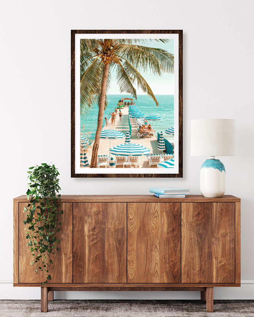 Framed Artwork  of a turquoise beach scene in Antibes with palm trees, beach umbrellas, and a boardwalk leading to the ocean. fine art photography by Paul Fuentes.