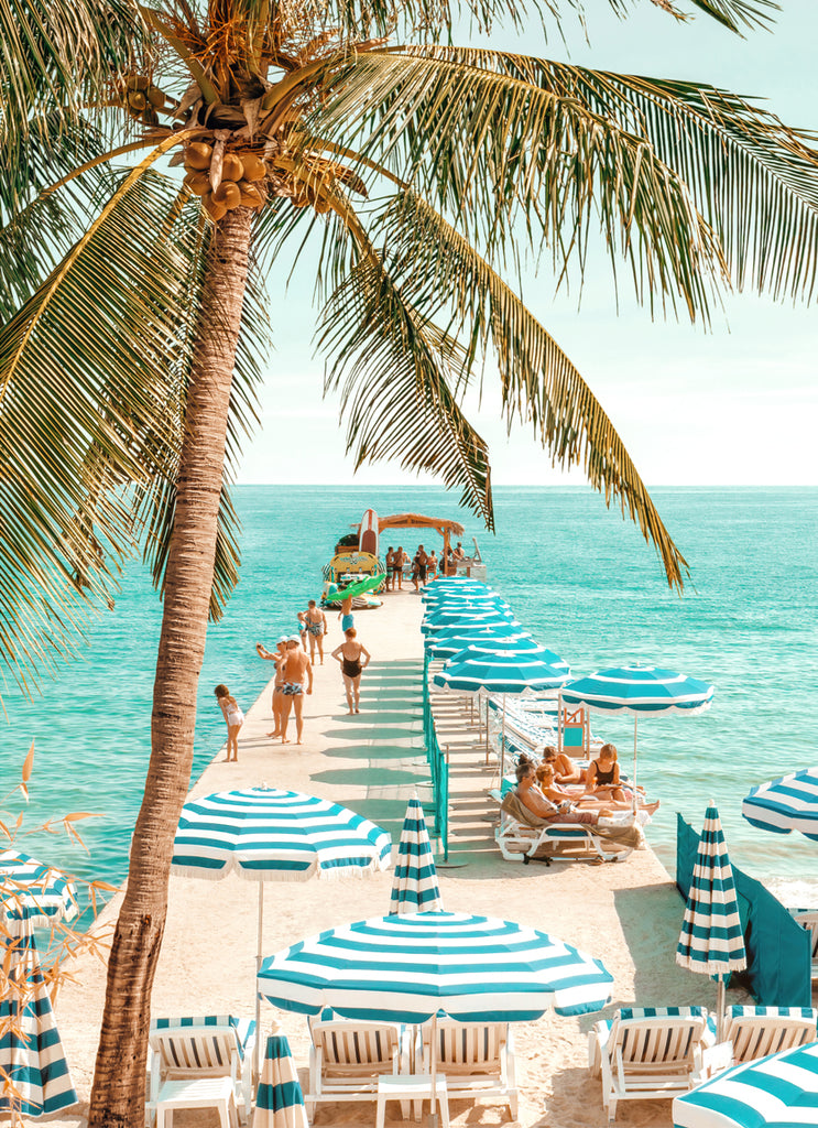 A vibrant print featuring a beach scene in Antibes with palm trees, beach umbrellas, and a boardwalk leading to the ocean. fine art photography by Paul Fuentes.