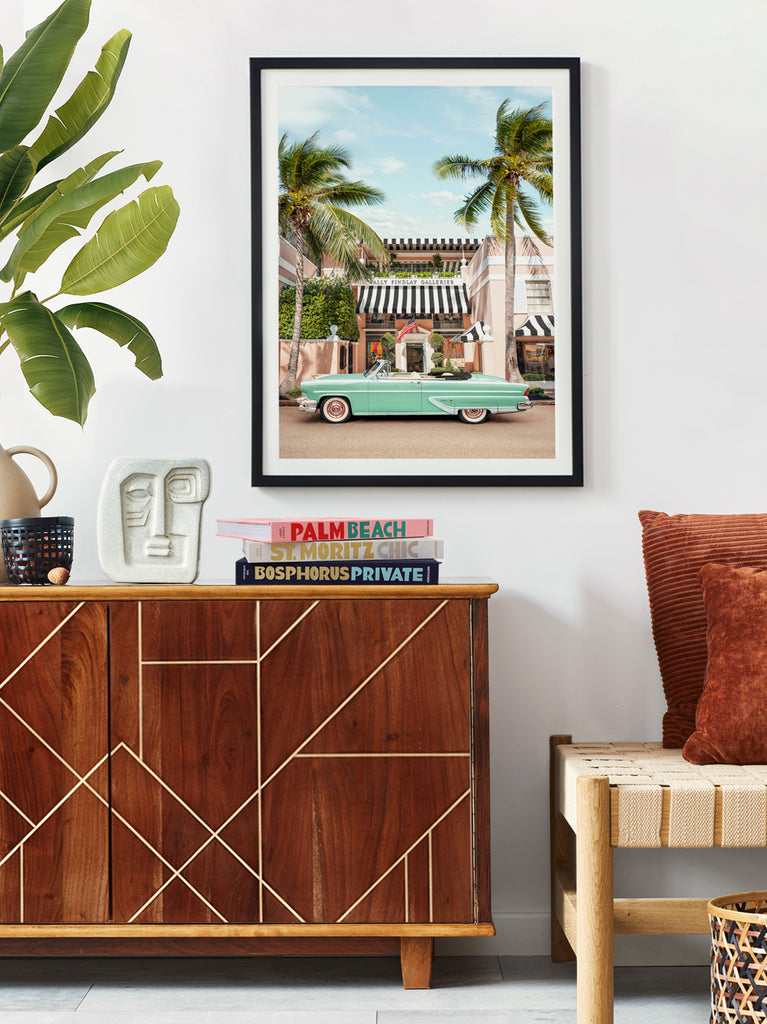 framed artwork by paul fuentes of palm beach gallery with classic green car in an interior with wooden side table
