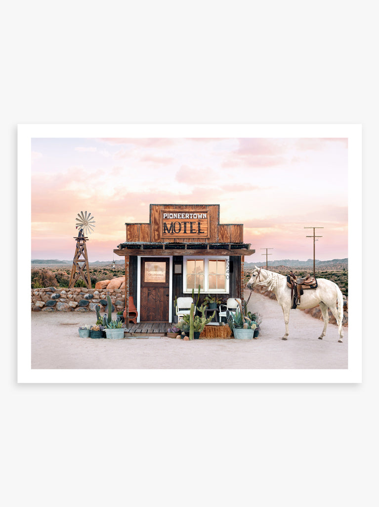 Cowboy town in the desert under golden light, fine art photograph by Paul Fuentes showcasing a desert landscape with a horse and cacti in the foreground.