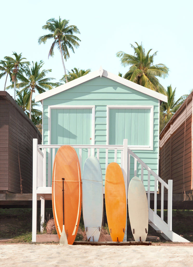Photography by Paul Fuentes showing a pastel green beach hut with surfboards leaning against it, set against a tropical backdrop with palm trees.