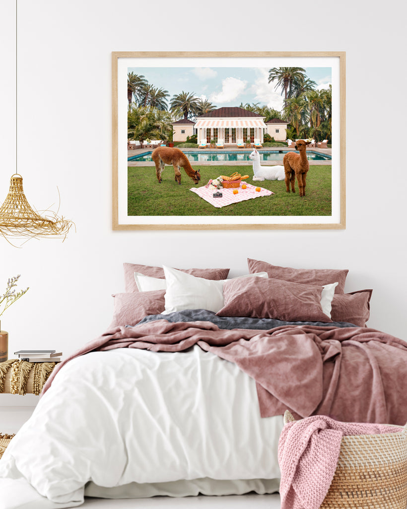framed artwork of two Llamas sitting around a picnic scene in a garden with pool and palm trees, fine art photography by Paul Fuentes.