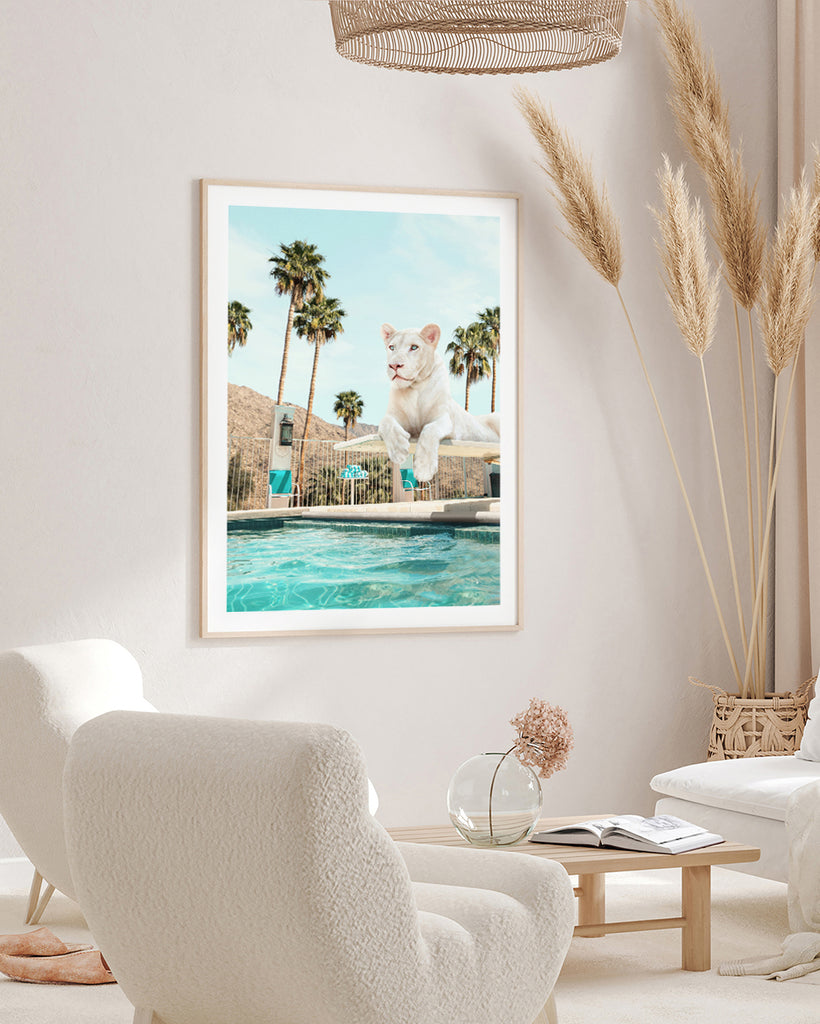 Framed artwork of a lioness on a diving board over a turquoise pool with palm trees in the background , fine art photography by Paul Fuentes.